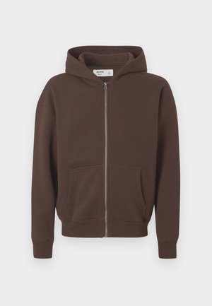 Rudas zip-up džemperis, pagamintas iš minkštos medžiagos. Turi kengūros tipo kišenę, guminiais rankogaliais ir reguliuojamą kapucę su raišteliu.