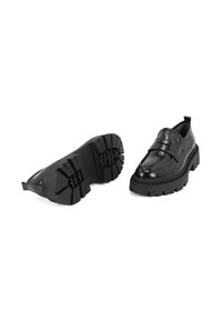 Zwarte leren schoenen met een stevige zool en een gespsluiting, voorzien van een glad bovenwerk, een gestructureerde rubberen buitenzool en een trekstaafje aan de hiel.