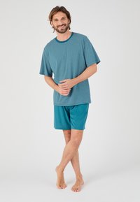 Conjunto de ropa de estar por casa para hombres que incluye una camiseta de manga corta a rayas en color verde azulado y pantalones cortos lisos a juego, fabricado con un tejido suave y transpirable.