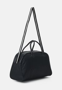 Sort duffelbag med en glat tekstur, rund form, top-håndtag og en lang, stribet skulderrem i sort og hvid.