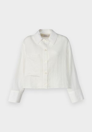 Zkrácená bílá lněná košile s špičatým límcem, přední kapsou a zapínáním na knoflíky. Dlouhé rukávy s kontrastním detailem na manžetách.