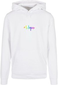 Biela mikina s klokaním vreckom, s hashtagem "#Hope" v dúhovom prechode farieb naprieč hrudníkom.