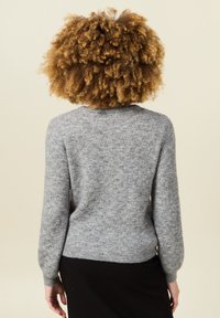 Grau gestrickter Pullover mit einem strukturierten Muster, Rundhalsausschnitt und langen Ärmeln. Der Saum ist körpernah geschnitten, und das Material wirkt weich und leicht.