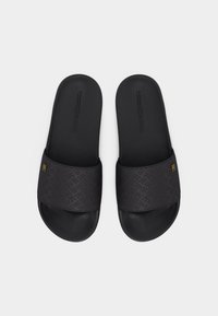 Schwarze, offene Slip-On-Sandalen mit strukturierten Fußbetten, geprägten Riemen und kleinen goldenen Logoakzenten auf jedem Riemen.