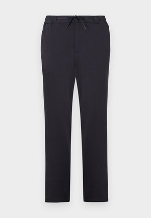 Pantalons de sport noirs en tissu doux avec une taille élastique, un cordon de serrage ajustable et une coupe droite. Aucun motif ni embellissement visible.