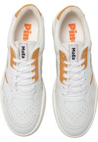 White leather sneakers with tan suede accents, flat white laces, perforated toe design, and a soft, textured interior. Branding visible on sides.