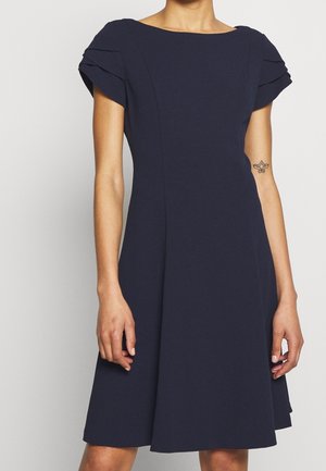 Navy blauwe jurk met korte, geplooide mouwen, een aansluitend lijfje en een uitlopende rok. Gemaakt van een gladde stof met een bootnek en naaddetails.
