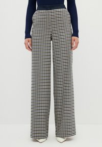 Kalhoty širokého střihu s houndstooth vzorem v námořnické modré a béžové barvě. Vyrobeno z tkané látky s hladkým povrchem a přiléhavým pasem.