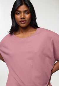 Przesadnie duża różowa bawełniana koszulka z szerokim dekoltem i krótkimi rękawami, charakteryzująca się gładką fakturą i luźnym krojem.