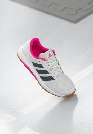 Chaussure de sport blanche avec des accents roses et des rayures noires, tige en mesh texturé, lacets blancs et semelle en caoutchouc naturel.