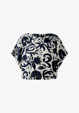 Blouse blanche à manches courtes avec une coupe ample, présentant des motifs floraux et feuillus abstraits noirs audacieux.