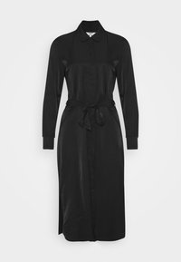 Robe noire à manches longues avec col, ceinture à la taille, fentes latérales et texture satinée lisse, présentant un design élégant et structuré.