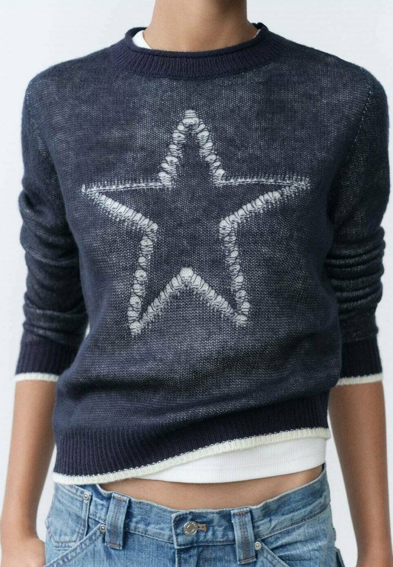 Marineblauwe gebreide trui met een wit sterpatroon aan de voorkant, geribbelde manchetten en zoom, en een ontspannen pasvorm met een ronde hals.