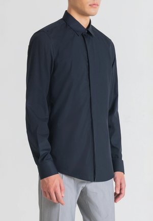 Camicia blu navy con bottone, realizzata in tessuto morbido, caratterizzata da un colletto classico, maniche lunghe e un design essenziale senza motivi.
