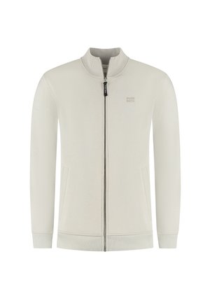 Lichtbeige zip-up jack met hoge kraag, textuurstof, zijzakken en subtiele branding op de borst. Geribbelde manchetten en zoom.