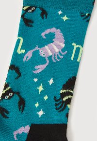 Turquoise socks featuring a pattern of purple lobsters and black scorpions, accented with green and white stars. Smooth knit texture.