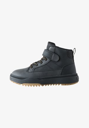 Sneaker nera alta con colletto imbottito alla caviglia, cinturino in velcro, lacci neri e beige e suola in gomma resistente color sabbia.