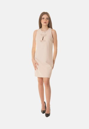 Abito beige senza maniche con una forma aderente, caratterizzato da tre fiocchi decorativi lungo il décolleté e un sottile dettaglio a chiave sul petto.