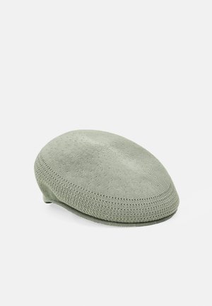 Knit beret-style cap in muted green. Smooth texture with a round, flat shape and detailed stitching along the edge. No visible logos.