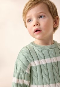 Mint green knit sweater with white stripes, featuring a textured cable pattern. Round neckline and ribbed cuffs.