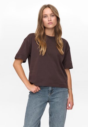 Brown cotton t-shirt with short sleeves, crew neckline, and relaxed fit, paired with blue denim jeans. Simple design, no patterns or accents.