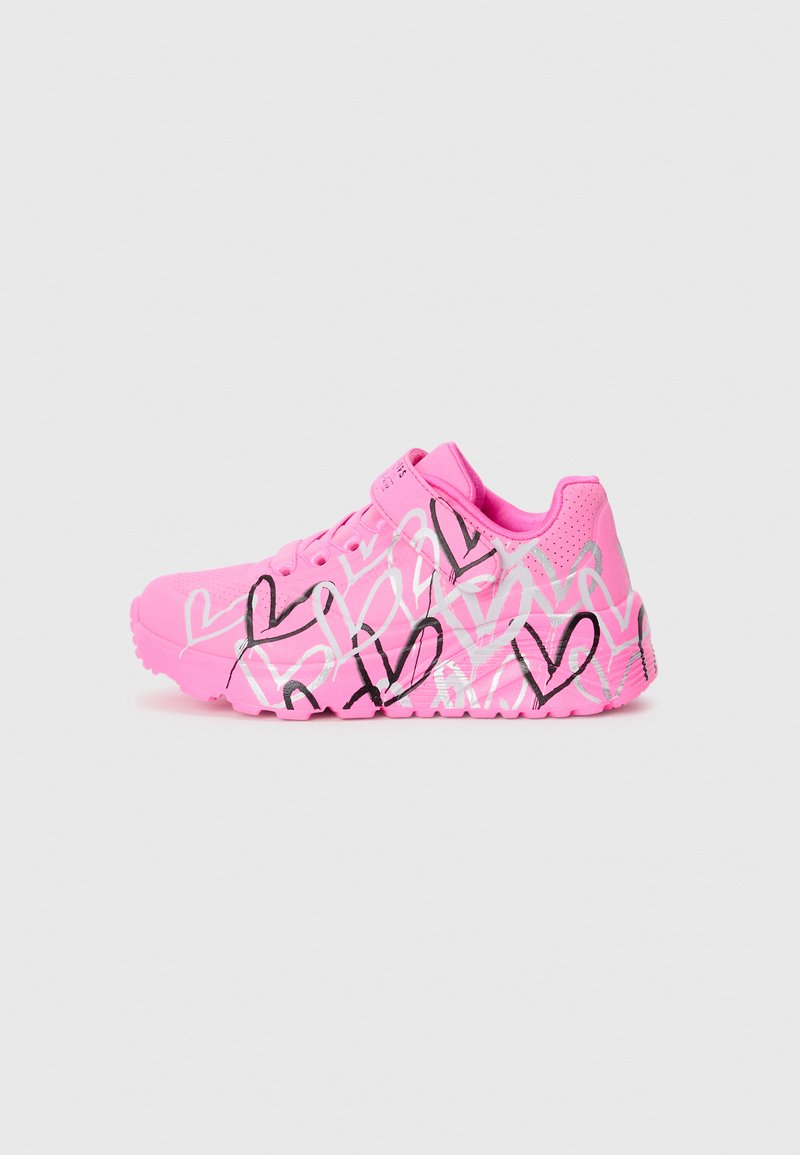Scarpa sportiva rosa con tomaia in rete, suola in gomma e motivo a cuore nero disegnato a mano. Progettata con una fascia sicura sul collo del piede.