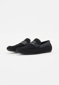 Mocassins noirs en matériau en maille respirante, avec une bande en cuir lisse et une semelle en caoutchouc plate pour une meilleure adhérence.