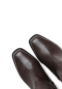 Brown leather cowboy boots with a square toe, smooth texture, and minimal hardware. The design features a high shaft and slim silhouette.