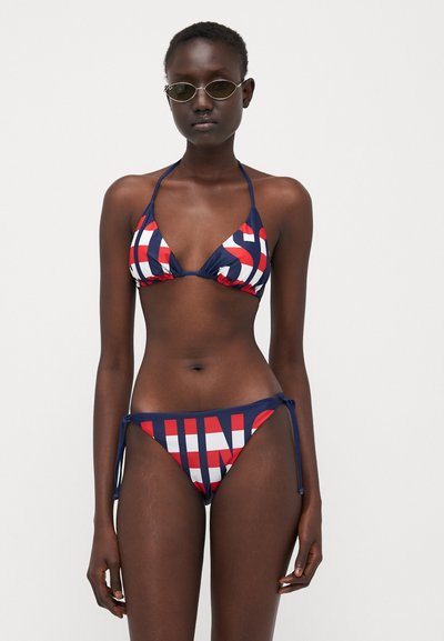 Tamsiai mėlynas bikini maudymosi kostiumėlis su raudonais ir baltais ryškiais tekstiniais raštais. Trys kampinis viršus ir šoninio rišimo apatiniai. Lygi tekstūra, reguliuojami raiščiai.