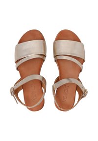 Flache Sandalen mit einer metallisch goldenen Oberfläche, ausgestattet mit breiten Riemen und einem schmalen Knöchelriemen mit einer silbernen Schnalle auf einer braunen Sohle.