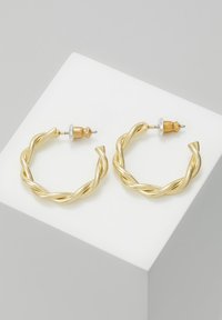 Twisted gold hoop earrings with a glossy finish, featuring a smooth texture and metal post back for secure wear.