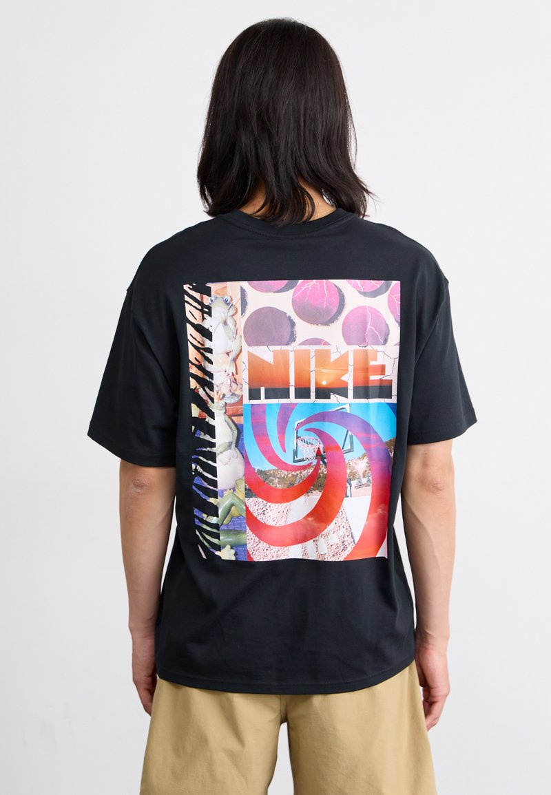 Svart bomull T-skjorte med en flerfarget grafisk design på baksiden, inkludert en fet "NIKE"-logo og abstrakte mønstre.