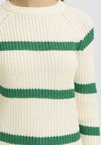Pull en maille crème avec des rayures horizontales vert foncé. Présente un col rond et un tissu texturé avec une coupe légèrement ample.