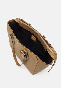 Brązowa torba typu tote ze skóry z zamkiem błyskawicznym, srebrnymi elementami i czarnym wnętrzem. Posiada podwójne uchwyty oraz logo wewnątrz.