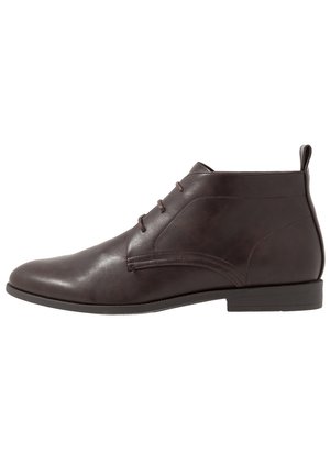 Dunkelbrauner Leder-Stiefelette mit drei Ösen für Schnürsenkel, abgerundeter Spitze und niedrigem Absatz, seitlich auf weißem Hintergrund gesehen.