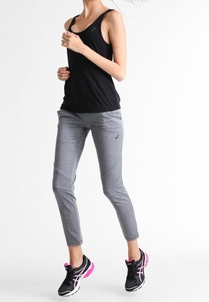 Black athletic tank top, gray fitted pants with textured panels, and black sneakers with pink accents. Designed for activewear.