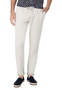 Beige Baumwollhosen mit elastischem Bund und Kordelzug, mit schmaler Passform und umgeschlagenen Bündchen, kombiniert mit dunkelblauen Espadrilles.