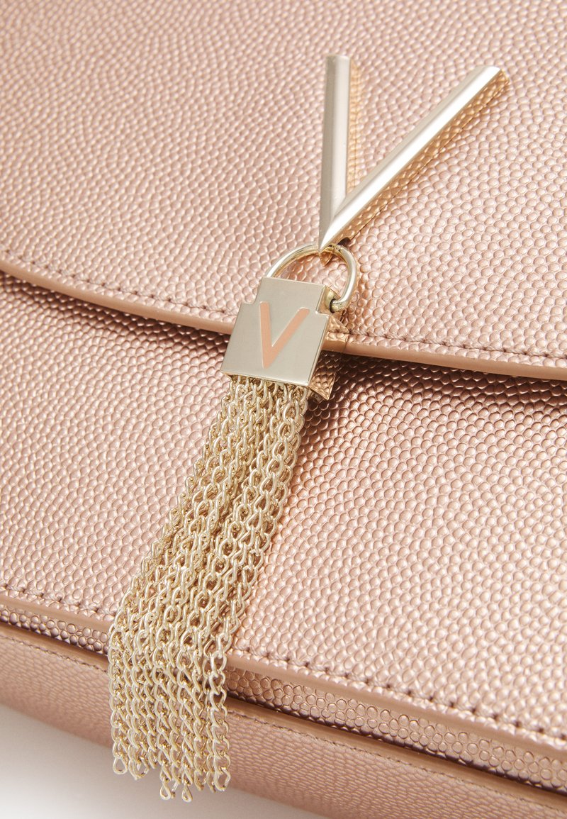 Sac en or rose avec surface texturée, featuring un gland en chaîne dorée et un accent en forme de V attaché à une fermeture à rabat.