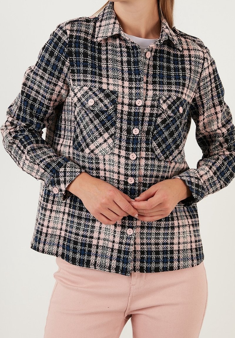 Camicia a quadri in nero, rosa e blu con due tasche sul petto, bottoni rosa e colletto. Tessuto morbido, peso medio.