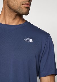 Μπλε ναυτικό T-shirt από βαμβακερό μείγμα, με στρογγυλή λαιμόκοψη, κοντά μανίκια και λευκό κεντητό λογότυπο στο αριστερό στήθος.