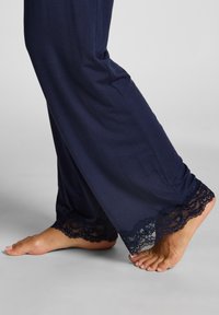 Pantalons de lounge navy en tissu doux avec une finition en dentelle aux chevilles. La dentelle présente un motif festonné, ajoutant du détail au design.