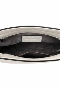 Interior de bolsa de cuero blanca con ribete negro, que presenta un parche con logo y un forro de tela oscura. Cierre de cremallera y un bolsillo adicional a la vista.