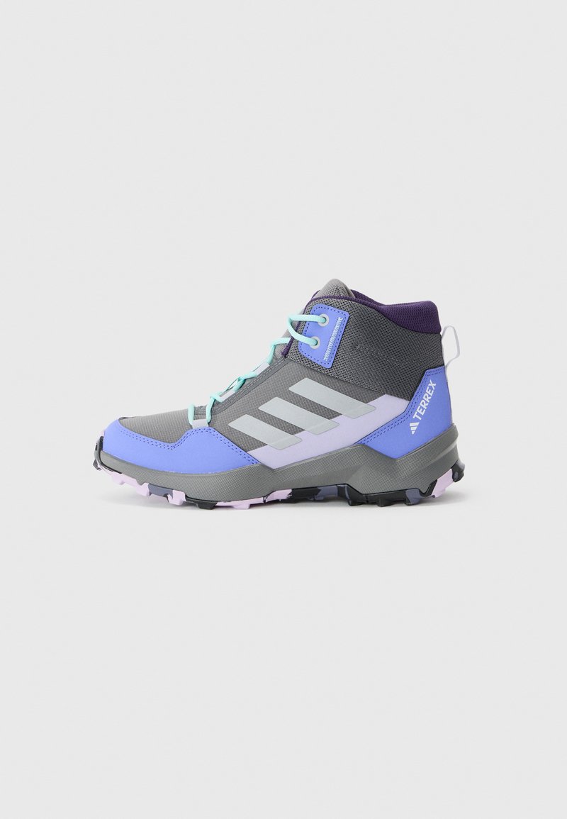 Bottes de randonnée grises et violettes avec un design à cheville haute, présentant une tige respirante, des empiècements texturés et une semelle robuste à crampons.