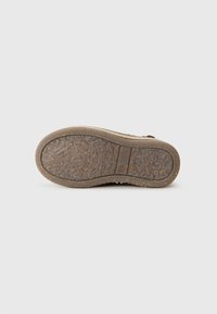 Suela de zapato con textura rugosa, color marrón terroso. Presenta un dibujo en el relieve para mayor agarre y una ligera curvatura en el talón.