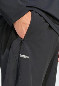 Zwarte sportbroek met een ritssluiting zak, ademende stof en het "climaCool" logo; gladde textuur en strak design.