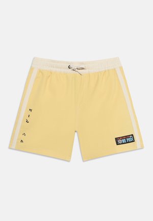 Κίτρινα μαγιό σορτς με μπεζ πλαϊνές ρίγες, ελαστική μέση με κορδόνι και μπαλώματα με το λογότυπο της σειράς One Piece στο πόδι.