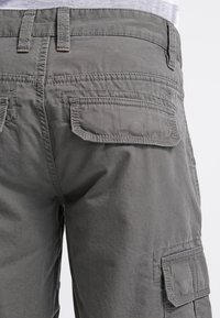 Pantaloni cargo grigi realizzati in un resistente tessuto di cotone. Presentano numerose tasche, una vestibilità comoda e sottili dettagli di cucitura.