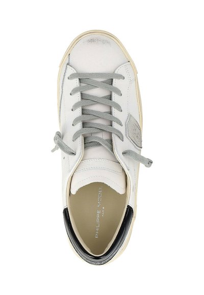 Baskets en cuir blanc avec lacets gris, languette de talon noire et nom de la marque "Philippe Model" visible à l'intérieur.