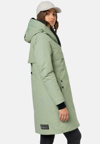 Light green insulated coat with a hood, black accents, side pockets, and a logo patch. Features a long, fitted design and smooth texture.