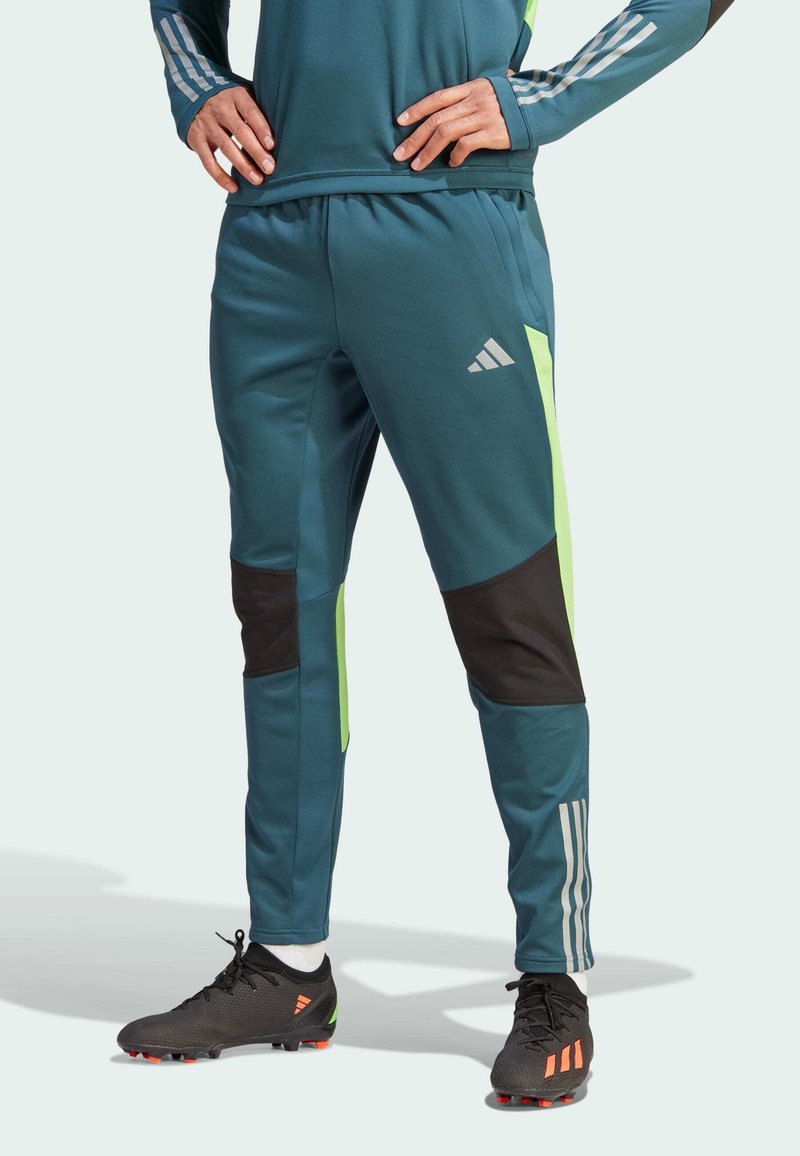 Teal sportieve broek met zwarte en neon groene accenten, voorzien van een elastische tailleband, sportieve lijnen en een Adidas-logo.